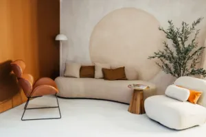 Scenografia w stylu japandi z beżowym kompletem wypoczynkowym, ścianą beżową pomalowaną w stylu lime wash i drugą ścianą w kolorze brązowym